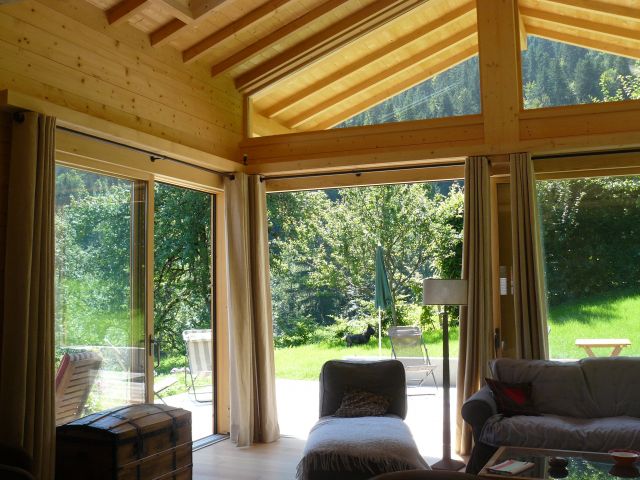 Une partie du salon,avec grandes baies vitrées ouvrant sur une grande terrasse en bois, exposée est-sud-ouest