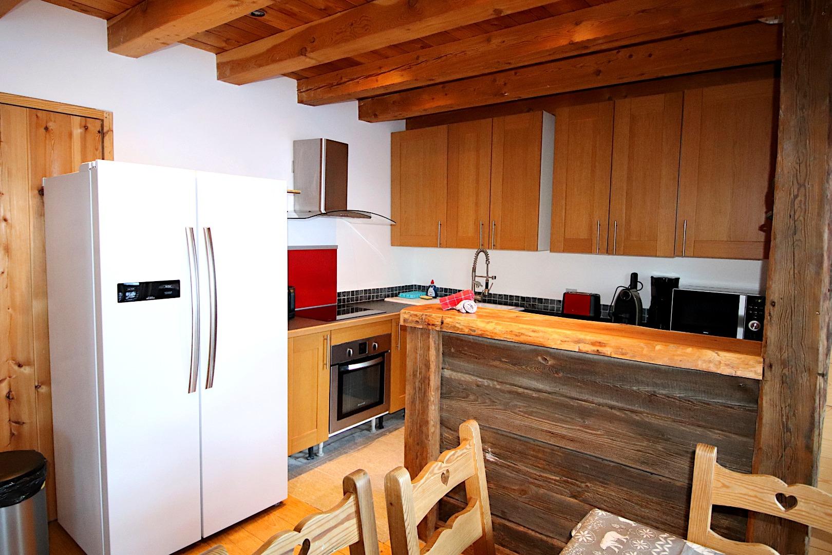 La cuisine toute équipée pour 12 personnes qui ouvre sur le salon. L'accès à la première terrasse se fait par la porte vitrée, où vous trouverez un salon de jardin avec table à manger, et le barbecue à charbon.