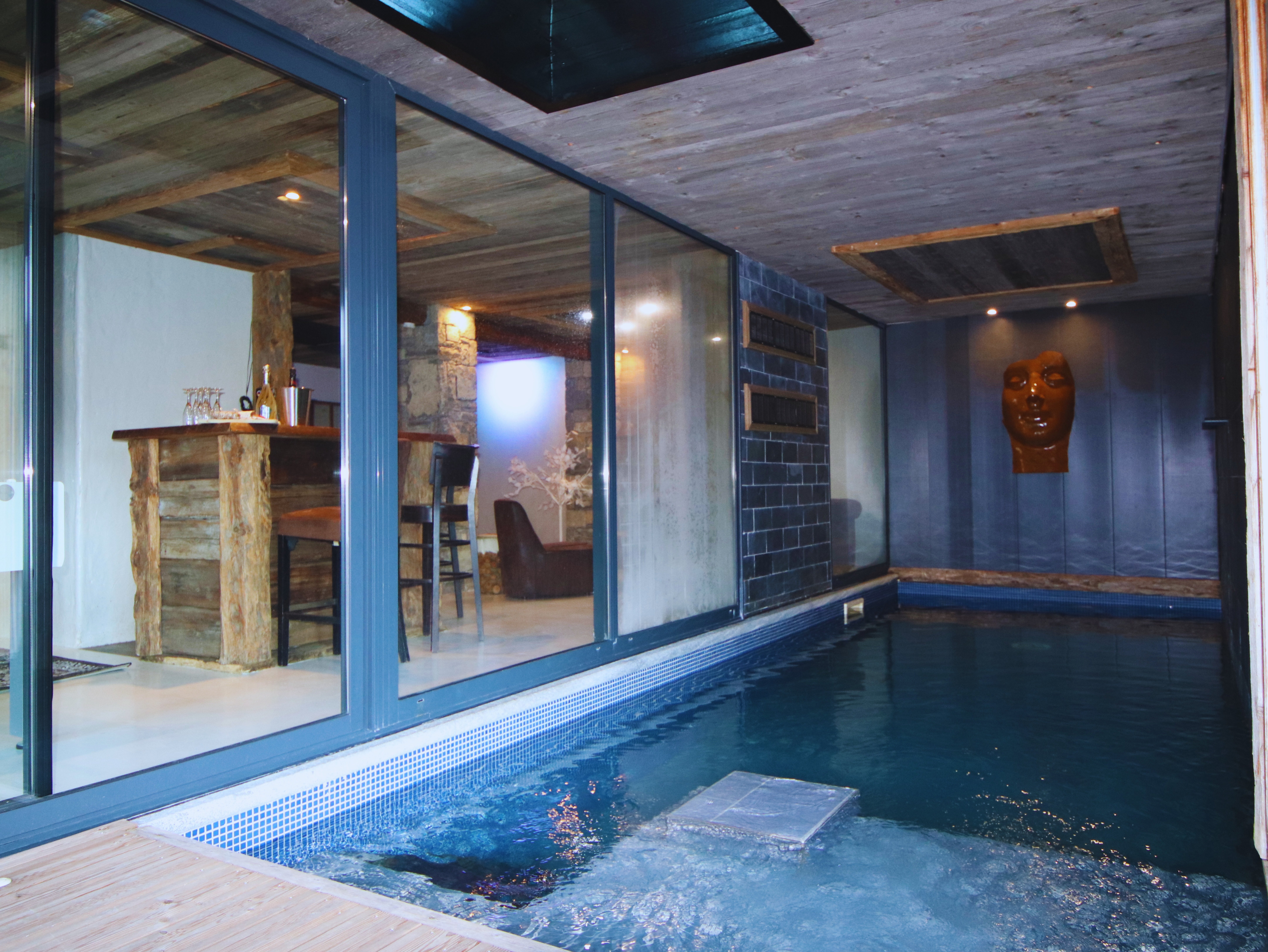 Piscine intérieure chauffée à 28°C au Chalet D à Vars, offrant une vue directe sur le bar privé de l'espace détente.