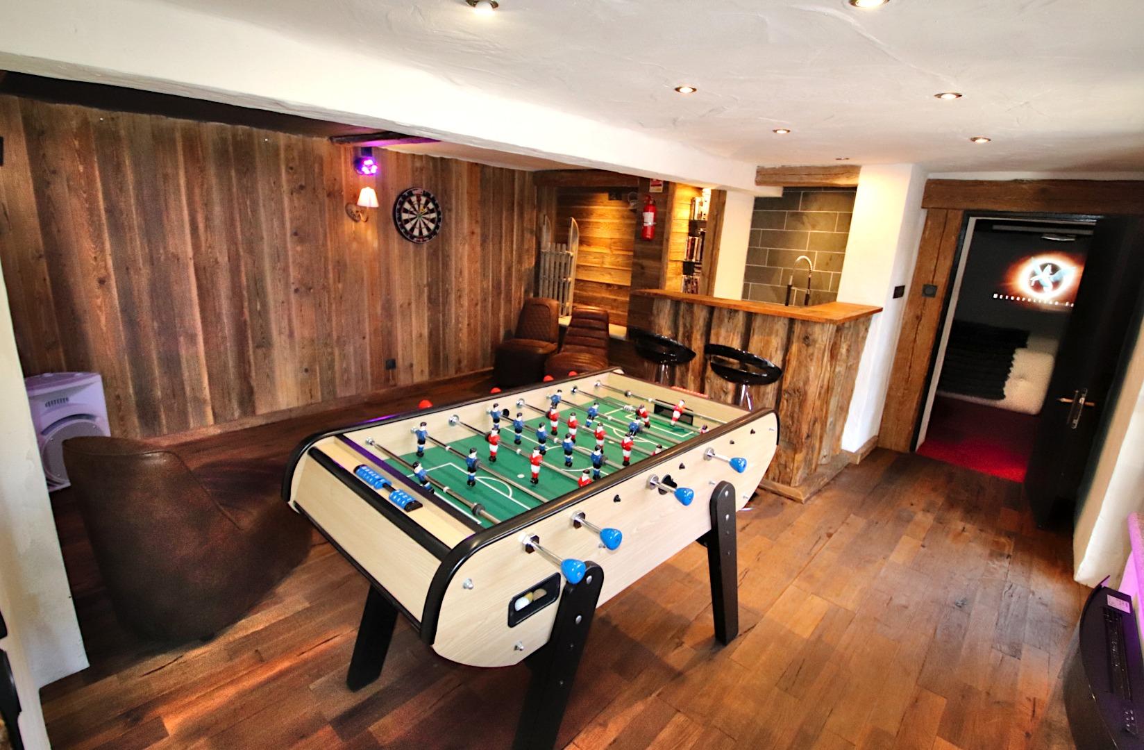Espace loisirs au R0, baby foot et jeu de fléchettes, bar et piste de danse qui donne sur la salle cinéma et terrasse extérieure où se trouve le spa de nage et les salons de jardin.