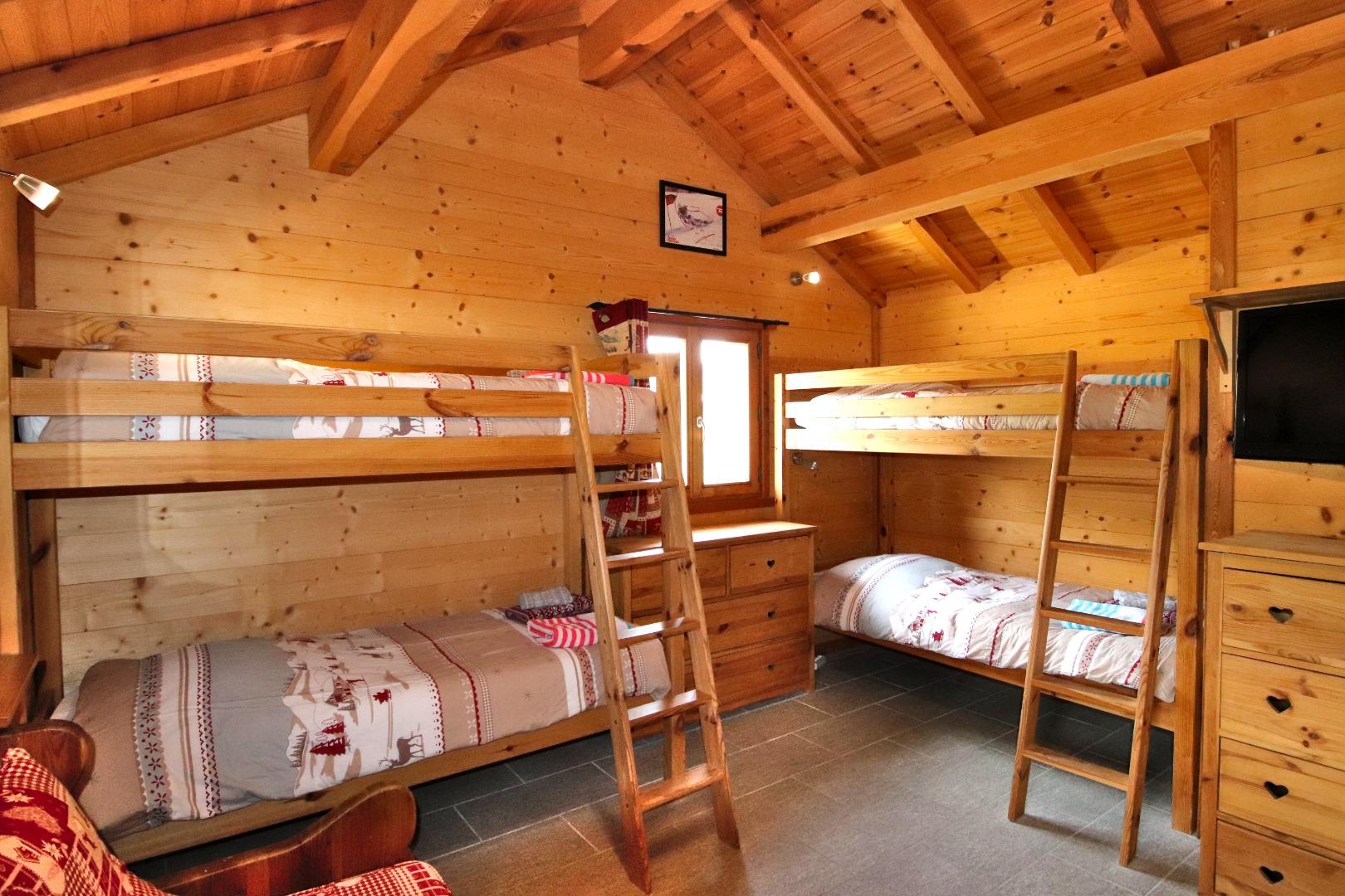La chambre 5 au R2 possède 4 couchages en lits superposés et un canapé-lit en 140. La salle de bain privative est attenante la chambre à droite, et est équipée d'une baignoire et des WC.